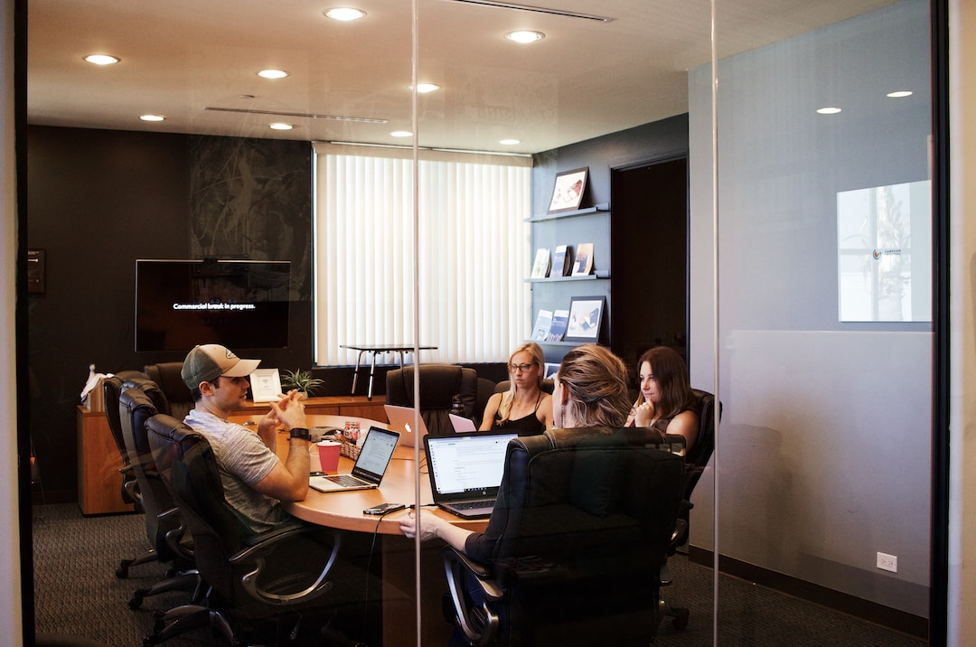 Four people sitting at a conference room table with laptops discussing the bottom of the funnel marketing